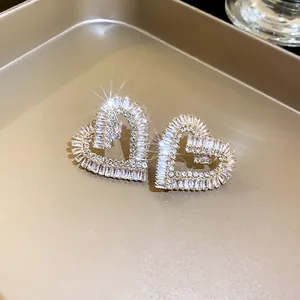 Macro di orecchini a cuore dorati scintillanti con zirconi e pietre in taglio baguette