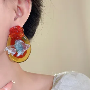 Detailed view of vintage koi and rose resin earrings on an Asian model's ear