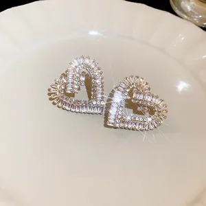 Primo piano di orecchini a lobo a forma di cuore in zircone su un piatto decorativo.