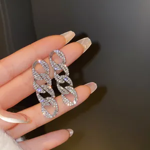 Dettaglio delle eleganti orecchini pendenti a catena color argento con pavé di strass brillanti