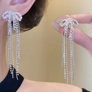 Detailed macro view of elegant silver-colored zircon bow-knot earrings with long chain tassels