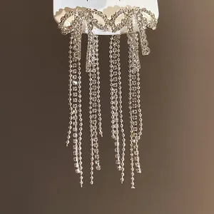 Detailed macro shot of elegant silver bow tassel earrings with sparkling zircons.
