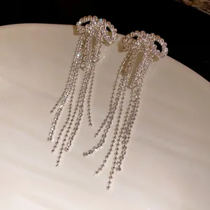 Close-up detail of silver-colored bowknot earrings featuring shimmering zircon tassel drops