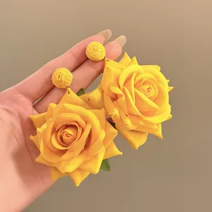 Detalle macro de pendientes de rosa de tela amarilla con diseño de rafia tejida