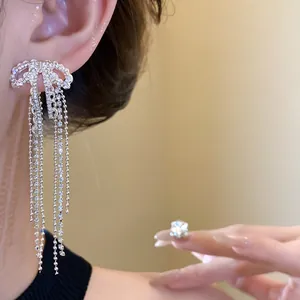 Elegant silver bow tassel earrings with sparkling white zircons shown on a model