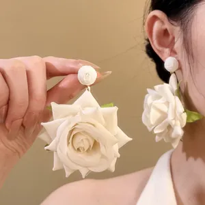 Primer plano de pendientes de flores de rosa en tela marfil con texturas delicadas