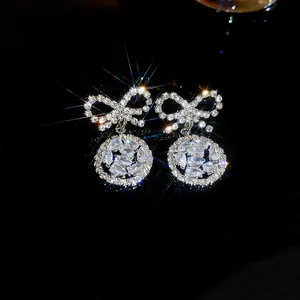 Dettaglio di orecchini a fiocco color argento con pendenti rotondi in strass lucidi