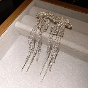 Detailed close-up of elegant silver zircon bow tassel earrings inside a premium jewelry box