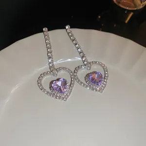 Dettaglio ravvicinato di orecchini a cuore in argento con pietre viola sfaccettate