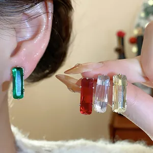 Close-up of colorful rectangular zircon stud earrings in green, red, and clear tones