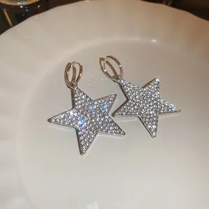 Dettaglio di orecchini a forma di stella scintillanti con incrostazioni di strass