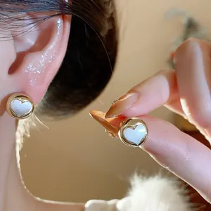 Close-up detail of elegant gold-toned heart stud earrings with pearlescent center