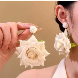 Detalle de cerca de pendientes de rosa de tela blanco crema en una modelo asiática joven.