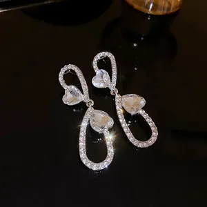 Primo piano dettagliato di eleganti orecchini a pendente a forma di cuore con strass lucenti.