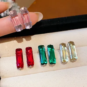 Close-up of rectangular zircon stud earrings in multiple colors within a velvet jewelry box