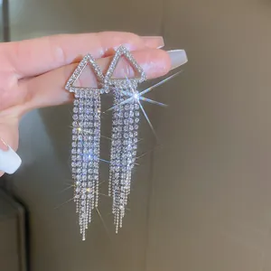 Dettaglio macro di orecchini a triangolo con nappe argentate e strass luccicanti