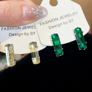 Detailed macro view of champagne and emerald green rectangular zircon stone stud earrings.