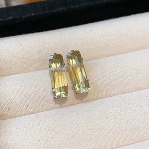 Detailed macro view of elegant rectangular yellow zircon stud earrings in beige jewelry box