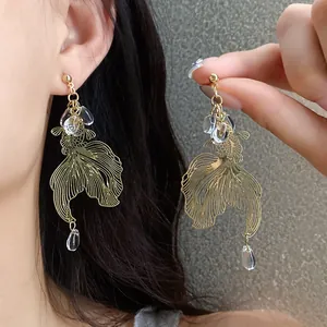Close-up of vintage koi fish earrings with gold finish and clear drop beads