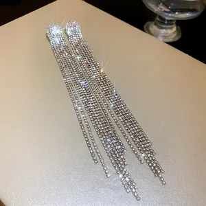 Close-up of elegant silver needle earrings with oval zircon and rhinestone tassels