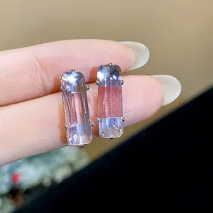 Close-up of elegant lavender rectangular zircon stud earrings held by female fingers