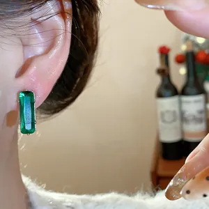 Close-up of elegant green rectangular zircon stud earring on ear for a luxury look