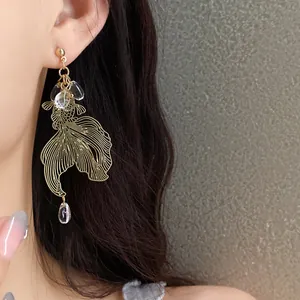 Close-up view of elegant gold-toned goldfish koi dangle earrings with crystal bead drops