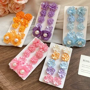 Detailed display of colorful floral stud earring sets with pearls on a wooden surface