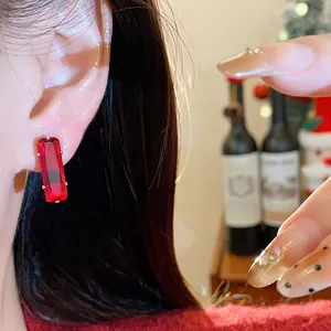 Close-up of minimalist red rectangular cubic zirconia stud earrings with silver pins.