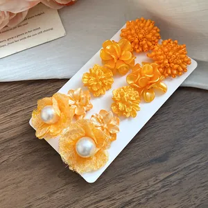 Close-up of vibrant orange 10-piece floral earring set featuring pearls and beads