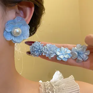 Close-up of blue floral earring and matching flower hair pins with pearl details