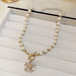 Close-up of pearl necklace with crystal flower pendant and gold T-bar clasp