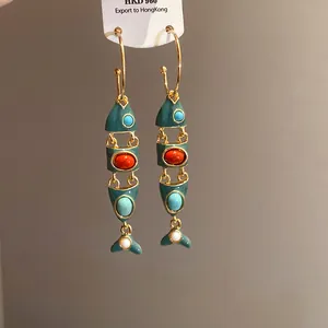 Dettaglio di orecchini a forma di pesce in smalto vintage con pietre colorate