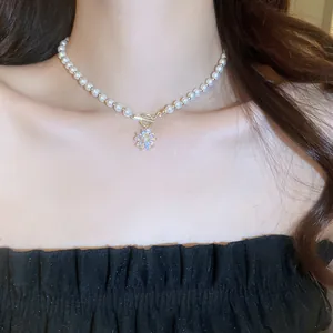 Close-up of a French vintage pearl necklace with a crystal flower pendant on a model