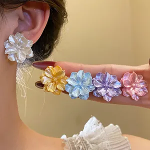 Detailed macro view showing shimmery multi-color pearl flower earrings on ear and hand
