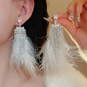Detailed macro view of silver needle zircon earrings with long white feather tassels