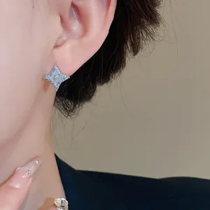 Detailed close-up of a sparkling silver four-pointed star stud earring worn on a model's ear