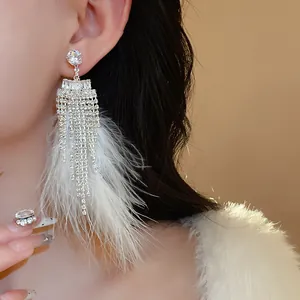 Macro detail of elegant silver-tone earrings with white feathers and long rhinestone tassels
