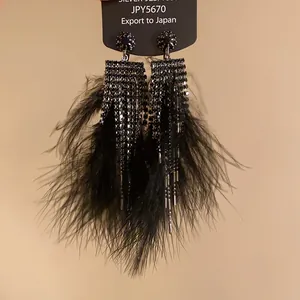 Detail view of elegant black feather tassel earrings decorated with sparkling rhinestones