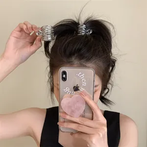Gros plan de pinces à cheveux géométriques en spirale argentée sur les cheveux d'une femme