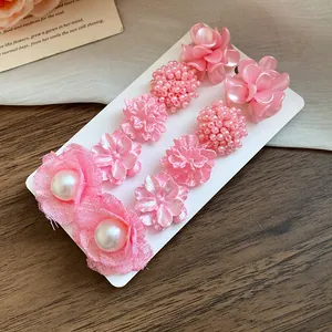 Macro detail of a 10-piece pink floral stud earring set featuring pearls and silver needles