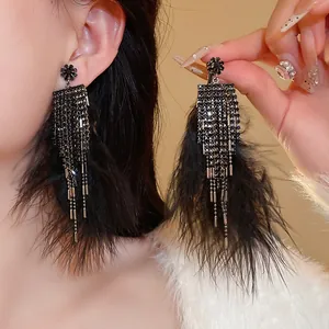 Close-up detail of elegant black zircon feather tassel earrings worn by a model