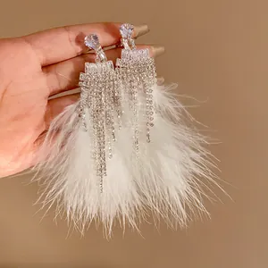 Close-up of elegant zircon tassel earrings with soft white feather trim details.