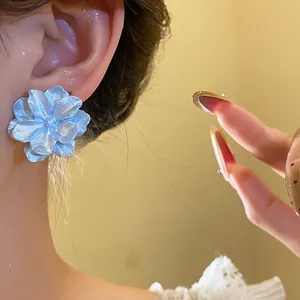 Close-up detail of light blue textured flower stud earring with elegant pearlescent finish