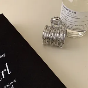 Détail d'une pince à cheveux argentée irrégulière avec une texture plissée et tissée