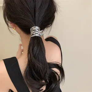 Gros plan d'une pince à cheveux en métal argenté plissé irrégulier sur une queue