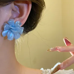 Close-up of elegant blue pearlescent flower ear stud worn on ear for stylish fashion look