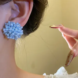 Detail view of a sweet blue beaded flower cluster stud earring worn on the ear