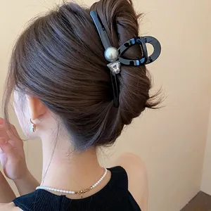 Elegant black hair claw clip with pearl and crystal charm worn by model.