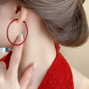 Primo piano dettagliato di orecchino a cerchio rosso geometrico indossato su modella